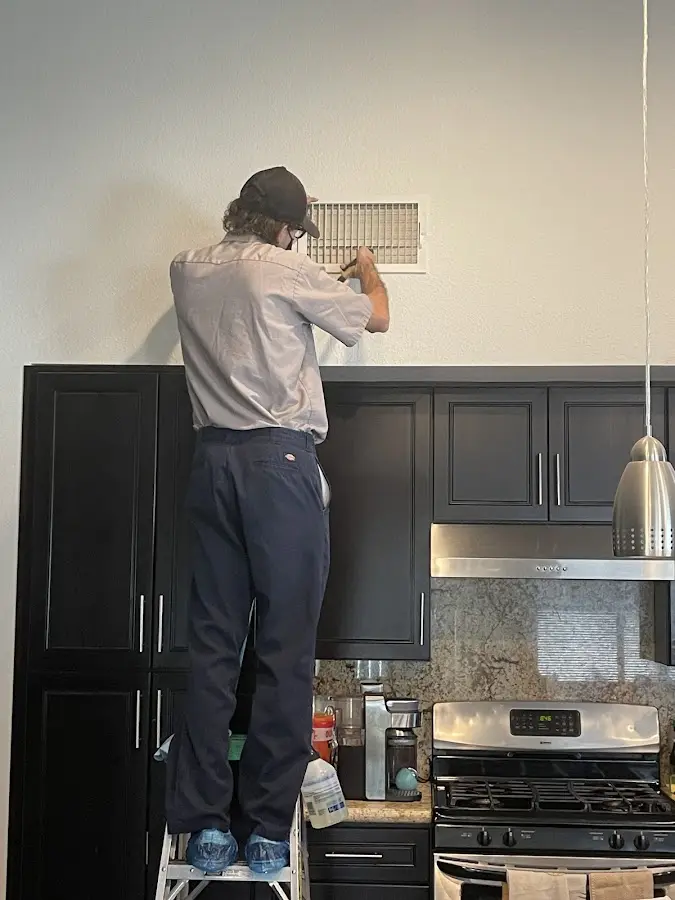 Technician inspecting an air vent during HVAC service in Pequannock